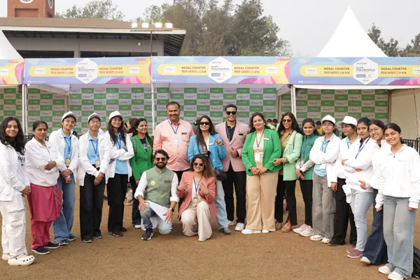 Group of marathon volunteers and participants posing together in front of the medal counter at a city marathon event